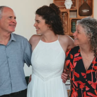 Shir Siegel, center, is embraced by her parents, former hostages Keith, left, and Aviva at Shir's wedding on August 7, 2025. (Paulina Patimer)